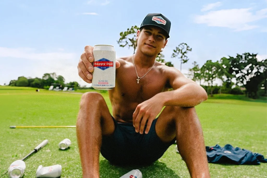 Who Is Big John Golfs? Age, Background and Big Deals Big John Golfs sitting on a golf course holding a can of Happy Dad